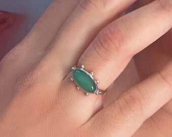 May include: A silver ring with a green oval gemstone set in a decorative silver setting.