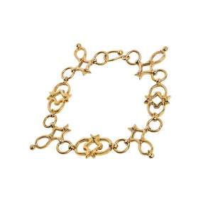 Puede incluir: Un brazalete de cadena de oro con un dise&ntilde;o &uacute;nico e intrincado que presenta c&iacute;rculos entrelazados y acentos en forma de estrella.
