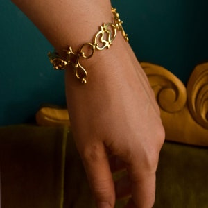 Puede incluir: Un brazalete de oro con un dise&ntilde;o delicado e intrincado. El brazalete est&aacute; hecho de c&iacute;rculos abiertos y corazones unidos.