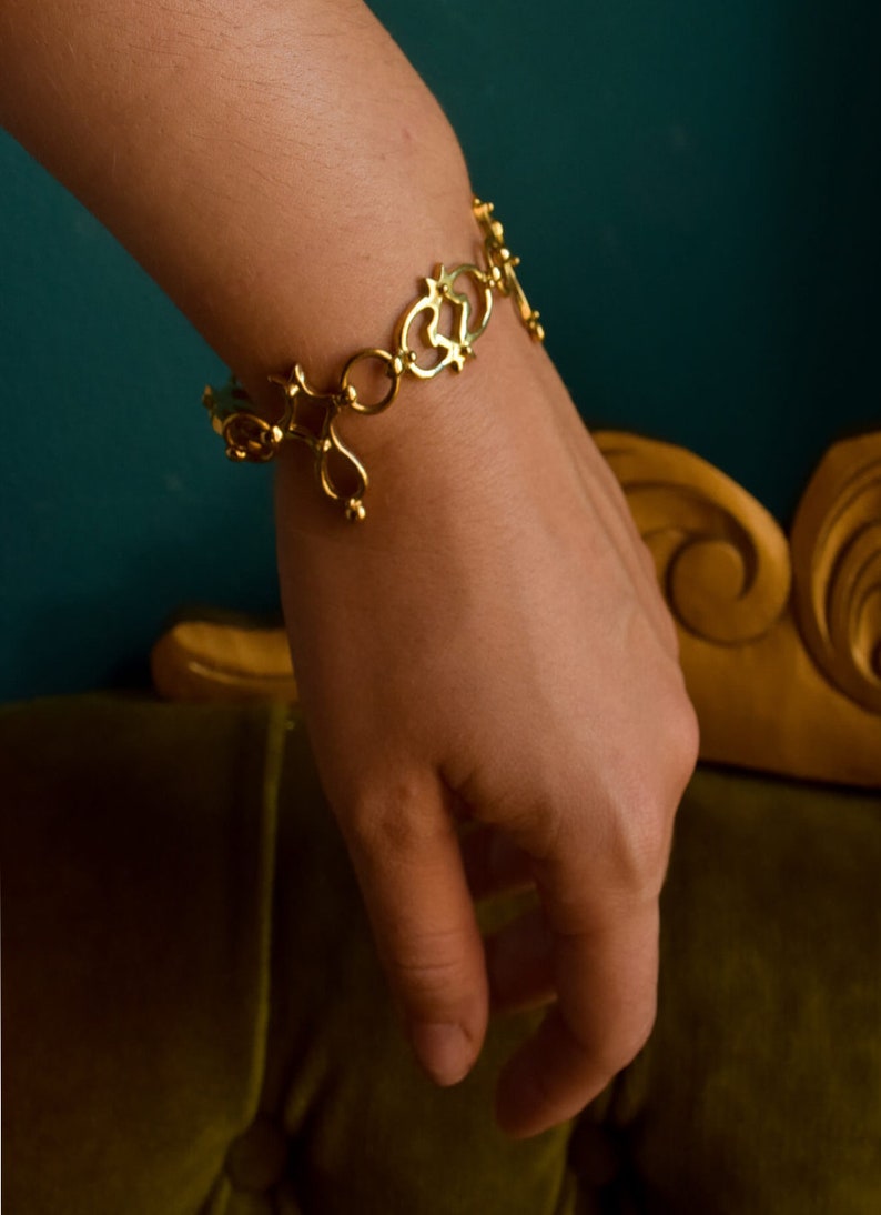 Puede incluir: Un brazalete de oro con un dise&ntilde;o delicado e intrincado. El brazalete est&aacute; hecho de c&iacute;rculos abiertos y corazones unidos.