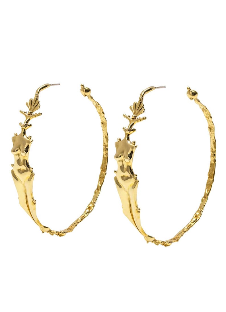 May include: A pair of gold hoop earrings with a textured finish. Each earring features a sculpted female figure with a floral design at the top.