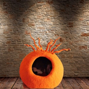 Peut inclure: Lit de chat en feutre orange avec une ouverture ronde et un design unique de vrilles en feutre s'&eacute;tendant du haut.