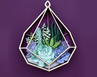 May include: A wooden geometric terrarium with a variety of green and purple succulents inside. The terrarium is shaped like a teardrop and has a gold-colored frame.