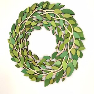 May include: A green paper wreath with leaves and branches. The wreath is made of multiple layers of paper, creating a 3D effect.