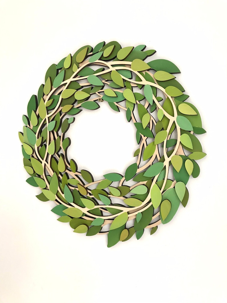 May include: A green paper wreath with leaves and branches. The wreath is made of multiple layers of paper, creating a 3D effect.