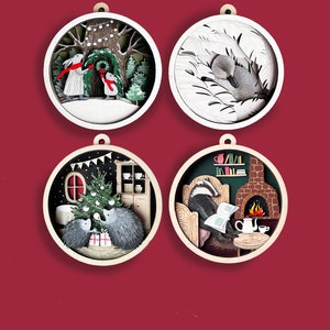 May include: Four round wooden ornaments with paper cut-out designs. The first ornament features two rabbits in a snowy forest. The second ornament features a swan in a nest of feathers. The third ornament features two hedgehogs decorating a Christmas tree. The fourth ornament features a badger reading a book by a fireplace.
