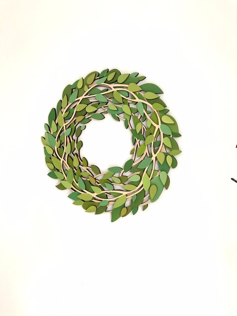 May include: A green paper wreath with leaves and branches, perfect for a spring or summer decor.