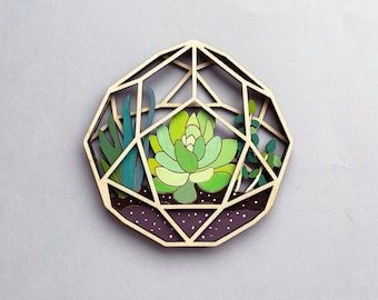 May include: A wooden geometric terrarium with a green succulent plant inside. The terrarium is painted with brown and white accents and has a geometric design.