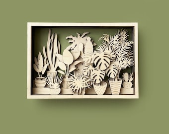 May include: A wooden shadow box art piece featuring a variety of potted plants, including a monstera, a palm tree, and a cactus. The plants are cut out of wood and layered to create a 3D effect.