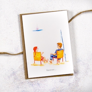 May include: A card with a watercolor illustration of two people sitting in chairs on a beach. The people are looking at each other and there is a sailboat in the distance. The text "forever..." is written at the bottom of the card.