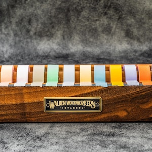 May include: A wooden tape dispenser with a label that reads "Walden Woodworkers Istanbul" and holds 12 rolls of colorful tape.