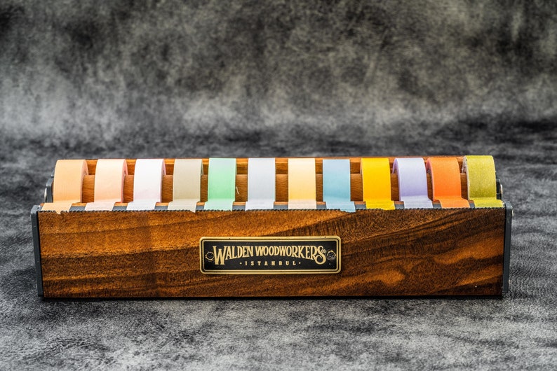 May include: A wooden tape dispenser with a label that reads "Walden Woodworkers Istanbul" and holds 12 rolls of colorful tape.