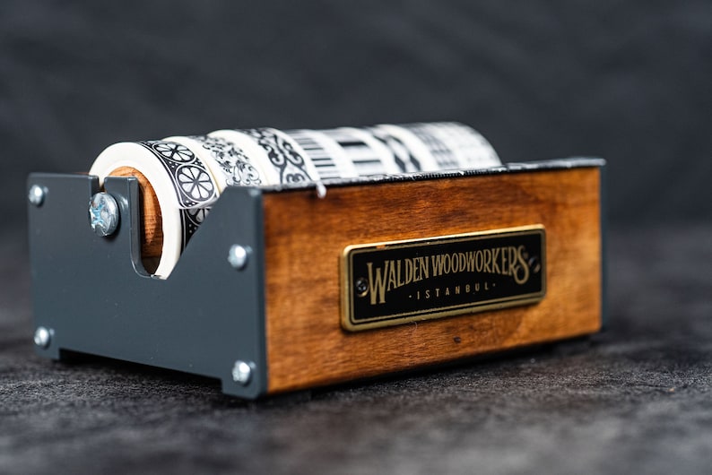 May include: A wooden and metal tape dispenser with four rolls of patterned washi tape. The dispenser has a label that reads "Walden Woodworkers - Istanbul."