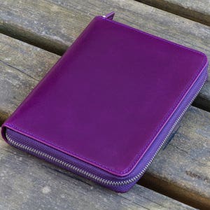 May include: A purple leather zippered wallet or clutch purse.