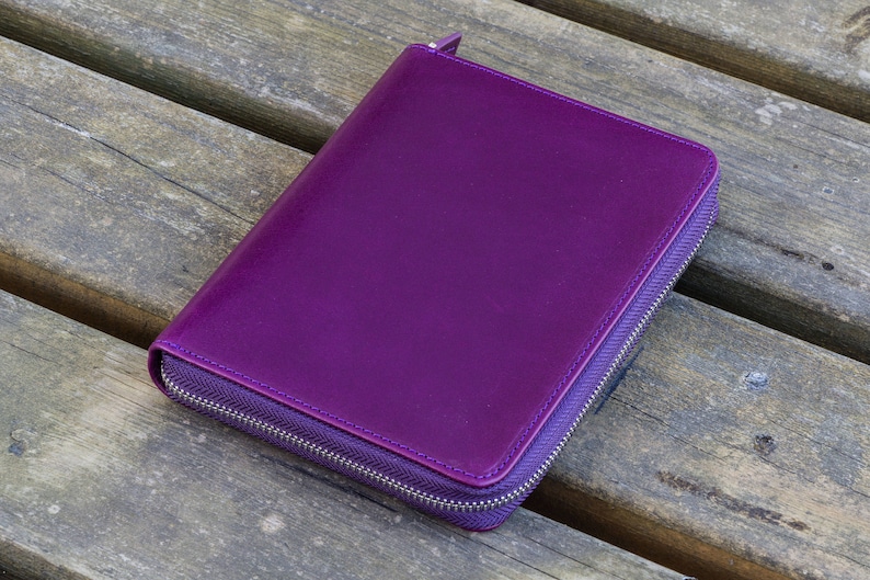 May include: A purple leather zippered wallet or clutch purse.