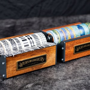 May include: Two wooden tape dispensers with black metal accents. Each dispenser holds multiple rolls of patterned washi tape. The dispensers have a brass plaque with the text "Walden Woodworkers Istanbul".