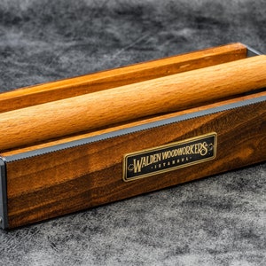 May include: A wooden rolling pin holder with a metal frame and a brass plaque that reads "Walden Woodworkers - Istanbul".