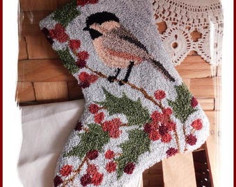 May include: A white and gray punch needle stocking with a chickadee bird and holly berries. The stocking is titled "Chickadee Punch Needle Stocking by Diane Knott LLC".