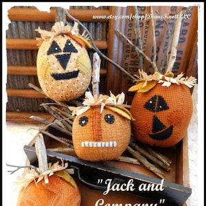 May include: Four handmade fabric pumpkins with stitched faces, in shades of orange and brown, arranged on a wooden tray with the text "Jack and Company" and "A Stitchery Pattern by Diane Knott LLC Copyright 2017".