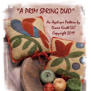 May include: Two felt applique pillow patterns, one with a bird and a branch, the other with a flower. The patterns are on a wooden bowl with embroidery floss in various colors. "A Prim Spring Duo" An Applique Pattern by Diane Knott LLC Copyright 2019 Diane's patterns are sold exclusively by www.etsy.com/shop/DianeKnottLLC