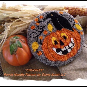 Peut inclure: Modèle de point de broderie pour une citrouille souriante avec un corbeau noir perché sur une branche. Le modèle s'appelle "Chuckles" et est de Diane Knott LLC.
