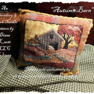 Könnte beinhalten: Ein besticktes Kissen mit einer Szene einer Scheune auf einem Feld mit Herbstlaub. Das Kissen ist aus braunem Stoff mit einem karierten Muster. Der Text "Autumn Barn" ist über dem Kissen geschrieben. Der Text "An Embroidery & Punch Needle Pattern by Diane Knott LLC (c) 2019" ist unter dem Kissen geschrieben.