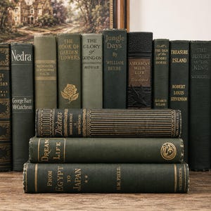 May include: A collection of vintage hardcover books in various shades of green, arranged with several standing upright and three stacked horizontally. The spines feature gold-toned lettering and decorative patterns, including titles like Treasure Island and Jungle Days.