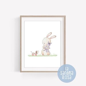 Puede incluir: Una ilustraci&oacute;n de acuarela de un conejo marr&oacute;n sosteniendo un burro morado, con un perro marr&oacute;n y blanco tirando de un carro rojo en el fondo. La ilustraci&oacute;n est&aacute; enmarcada en un marco marr&oacute;n claro.