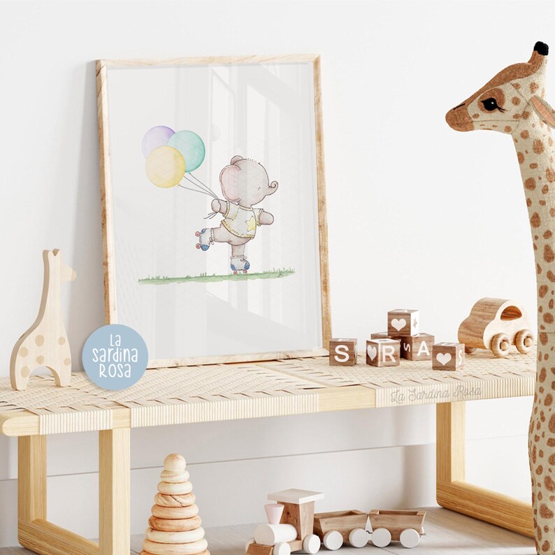 Puede incluir: Una ilustraci&oacute;n de acuarela de un elefante marr&oacute;n que lleva una camisa amarilla y patines, sosteniendo tres globos en azul, verde y morado. La ilustraci&oacute;n est&aacute; enmarcada y se muestra en un estante de madera con otros art&iacute;culos decorativos.