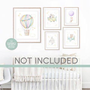 May include: A set of five watercolor prints featuring a hot air balloon, a plane, a fox with a balloon, a quote about places you'll go, and a bear in a plane. The prints are framed in light wood and are displayed on a white wall above a white crib.