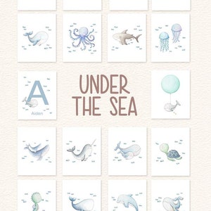 May include: A set of 12 watercolor illustrations featuring various sea creatures, including whales, a narwhal, a seahorse, a turtle, a jellyfish, an octopus, a shark, and a dolphin. The illustrations are surrounded by small blue fish and the text "UNDER THE SEA" is displayed in the center of the image.