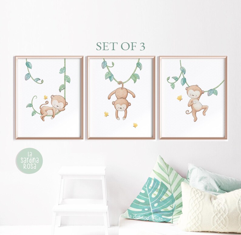 May include: Set of three watercolor prints featuring monkeys swinging on vines. The monkeys are brown with light brown faces and are depicted against a white background with green vines.