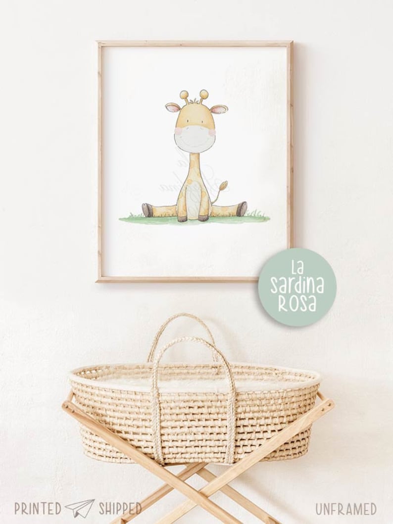 Puede incluir: Una ilustraci&oacute;n de acuarela de una linda jirafa sentada en un parche de hierba verde. La ilustraci&oacute;n est&aacute; enmarcada y colgada en una pared blanca. El texto "la sardina rosa" est&aacute; impreso en un c&iacute;rculo verde claro debajo del marco.