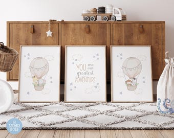 May include: Three framed prints with a light blue background and purple stars. The center print has the text "You are our greatest adventure". The other two prints feature a hot air balloon with animals inside.