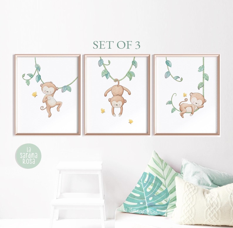 May include: Set of three watercolor prints featuring monkeys swinging on vines. The monkeys are brown with yellow accents and are surrounded by green leaves. The prints are perfect for a nursery or child's room.