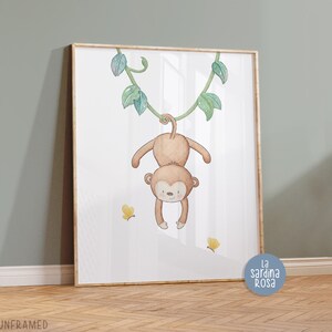 May include: A watercolor illustration of a monkey hanging from a vine with green leaves. The monkey is brown and has a cute face. There are yellow butterflies on the white background. The image is framed and has the text "La Sardina Rosa" in the bottom right corner.