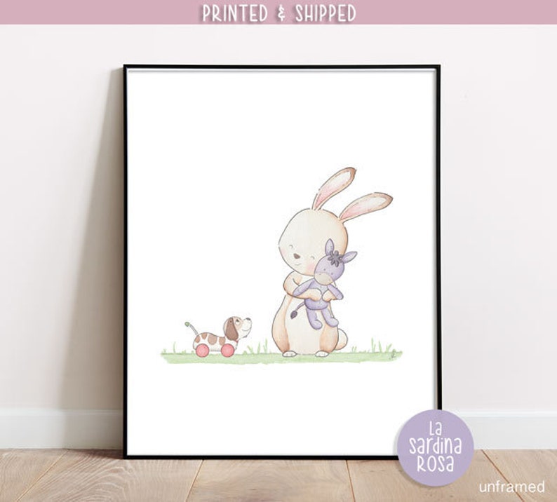 Puede incluir: Una ilustraci&oacute;n de acuarela de un conejo marr&oacute;n sosteniendo un burro de peluche morado. Un perro marr&oacute;n y blanco con ruedas rojas est&aacute; en el fondo. La ilustraci&oacute;n est&aacute; sobre un fondo blanco con un borde de hierba verde.
