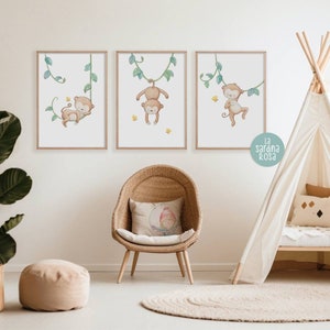 May include: Three framed prints of monkeys hanging from vines. The monkeys are brown and have yellow accents. The vines are green and have leaves. The prints are on a white wall with a white rug and a wicker chair with a pillow.