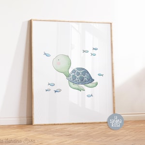 May include: A watercolor illustration of a green sea turtle swimming with blue fish. The turtle has a blue and gray shell and is surrounded by small blue fish. The illustration is on a white background and is framed in a light wood frame.