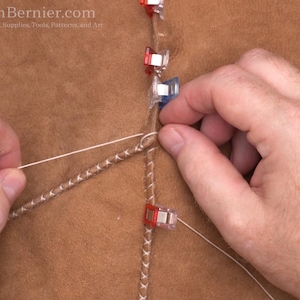 May include: Close-up of leatherworking with hands manipulating thread and leather. The image shows a detailed view of a sewing process, with the text "TonyAllenBernier.com" visible in the top left corner.