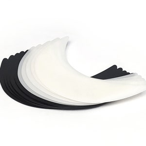 May include: A stack of white and black crescent-shaped fabric pads.