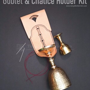 Op de afbeelding: Lederhandwerkset voor het maken van een kelk- of kelkhouder. De set bevat natuurlijk ongeverfd leer, naalden, draad en een online video tutorial. De set wordt getoond met twee gouden kelken en rood draad.