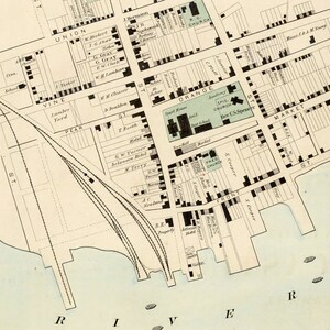 May include: A vintage map of a city with streets, buildings, and landmarks labeled. The map includes the names of streets like Union, Vine, Pear, Orange, Market, and Front. It also shows the locations of churches, a school, a hotel, and a lumber yard.