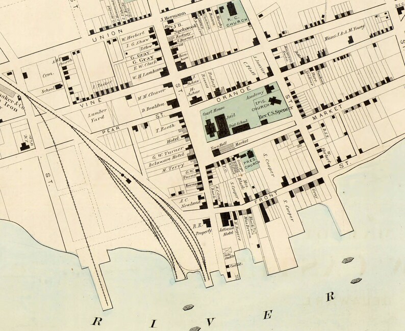 May include: A vintage map of a city with streets, buildings, and landmarks labeled. The map includes the names of streets like Union, Vine, Pear, Orange, Market, and Front. It also shows the locations of churches, a school, a hotel, and a lumber yard.
