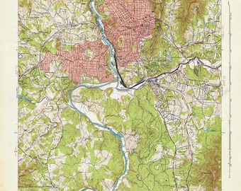 Pode incluir: Um mapa topográfico vintage de Asheville, Carolina do Norte, mostrando o layout da cidade, as estradas e as montanhas ao redor. O mapa é impresso em verde, marrom e azul, com linhas vermelhas indicando estradas e outras características. O mapa é intitulado "Asheville Quadrangle" e inclui o texto "United States Department of the Interior Geological Survey" e "United States Tennessee Valley Authority".