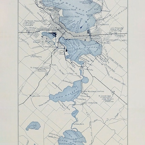 May include: A vintage map of Madison, Wisconsin, showing the lakes and surrounding areas. The map is printed in blue and white on a cream-coloured background. The map includes the names of the lakes, parks, and other points of interest. The map is titled "Issued by the Madison Association of Commerce, 1920."