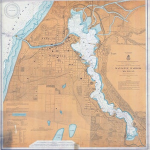 May include: A vintage map of Manistee Harbor, Michigan, showing the city layout, waterways, and surrounding area. The map is printed on a cream-colored paper with blue and brown ink. The title "Manistee Harbor, Michigan" is printed in the lower right corner.