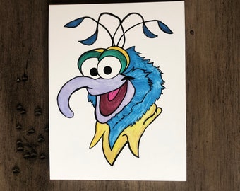 May include: A hand-drawn illustration of a blue, furry character with a long, purple nose, large eyes, and a yellow collar. The character has a whimsical, cartoon-like style.