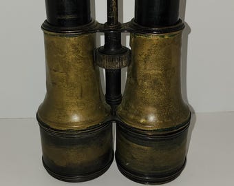 Könnte beinhalten: Antike Messing-Ferngläser mit schwarzen Akzenten. Das Fernglas hat einen zentralen Einstellknopf und ist in gutem Zustand.