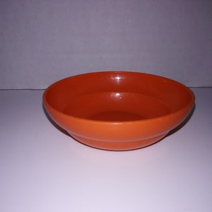 以下が含まれることがあります： オレンジ色のプラスチック製の小さなボウル。ボウルは丸く、滑らかで光沢のある仕上げになっています。
